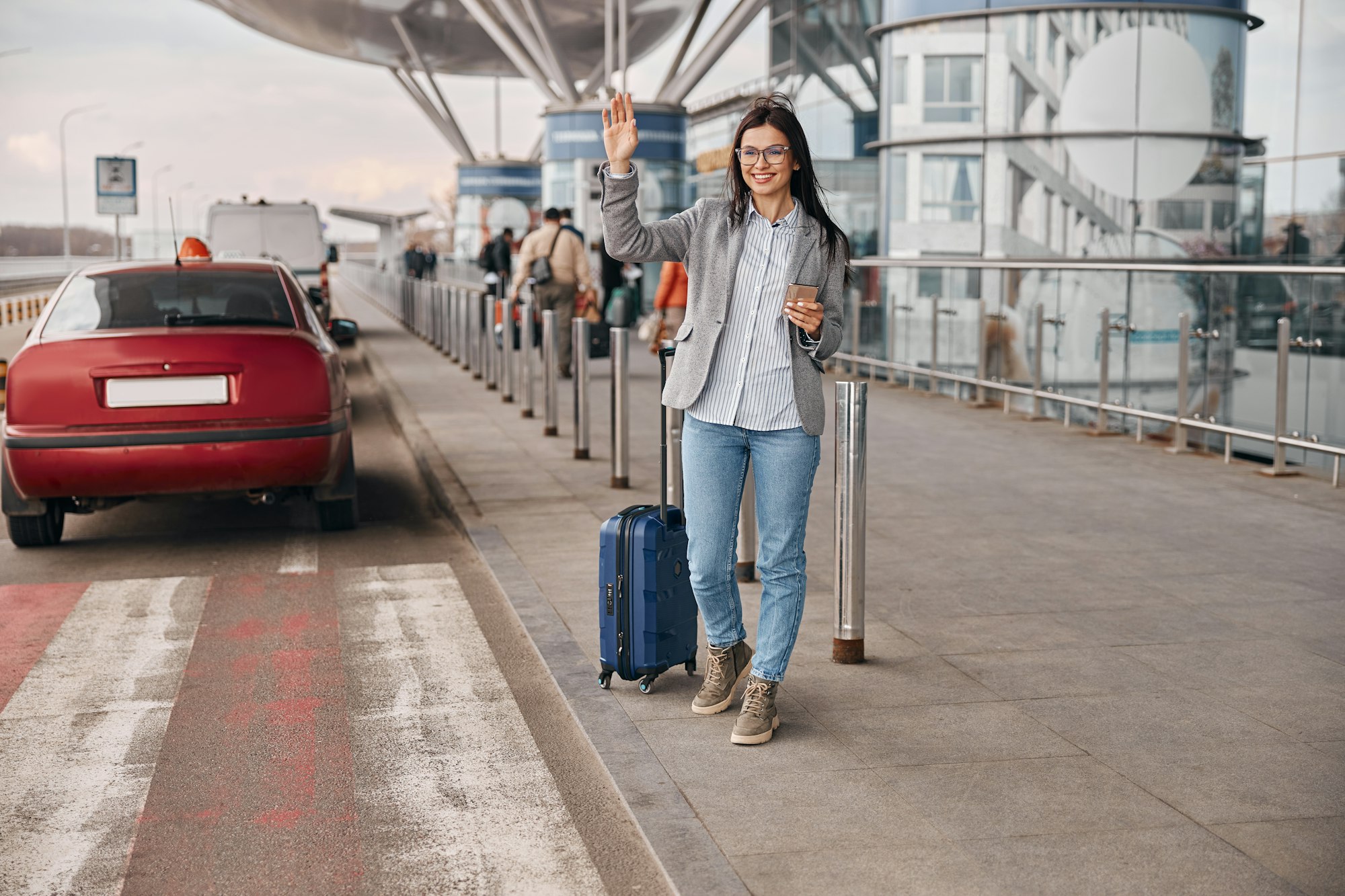 Happy caucasian woman traveller in airport terminal is taking a taxi