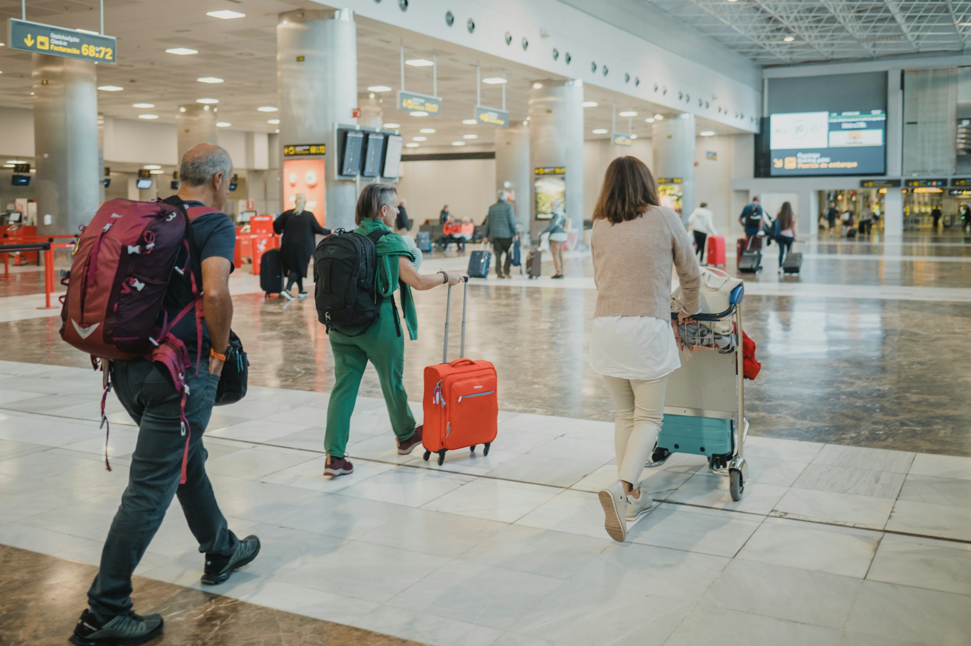 Unrecognizable people with luggage walking in departure hall of airport